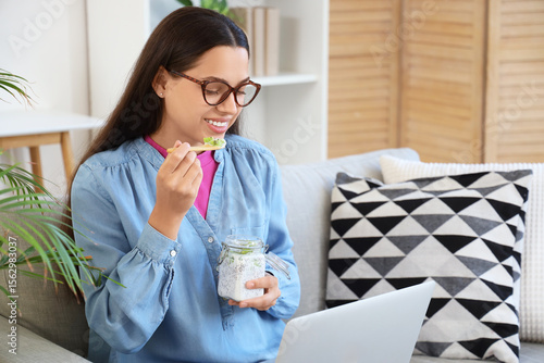 Young woman with laptop eat...