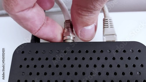 A coaxial cable slides into place-signal flows, silent but certain. Ventilated black device hums with quiet intent. Connection complete, energy in motion