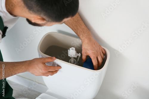 Foto Male plumber replacing fill valve in toilet tank, closeup