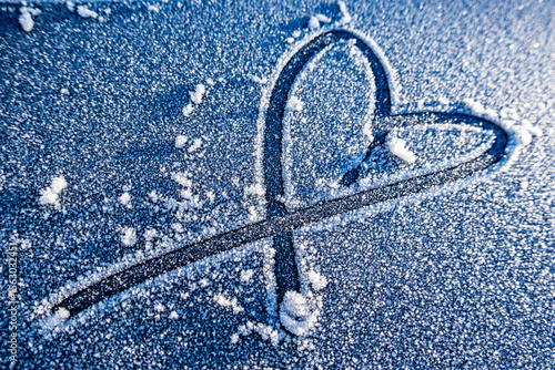 Bild auf Leinwand Heart shape drawn in frost on a cold winter morning with small stones on a gray