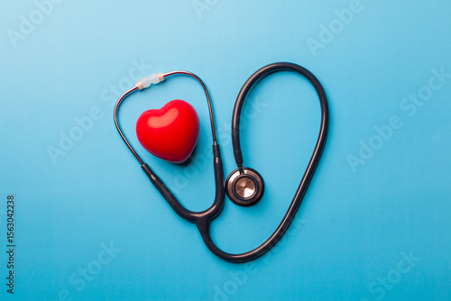  top view, Red heart shape exercise ball with doctor physician's stethoscope on blue background. hospital life insurance concept, world heart health day. doctor day