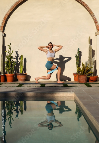 active young woman standing in pilates pose on mat near swimming