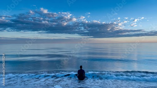 Person meditating on a beach at dawn