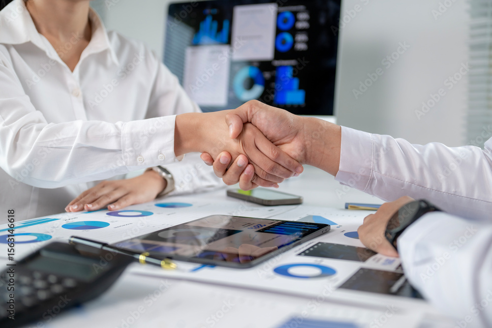 Fototapeta premium A woman shakes hands with another person in a business setting