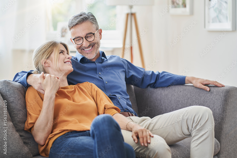 Happy couple holding hands on sofa at home Happy couple holding hands on sofa at home