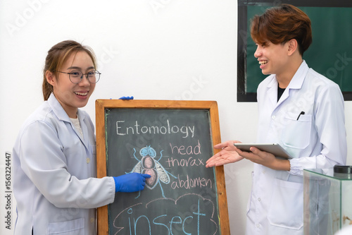 Fotografie Female Asian entomologist lecturing and presenting fly insect anatomy on blackbo