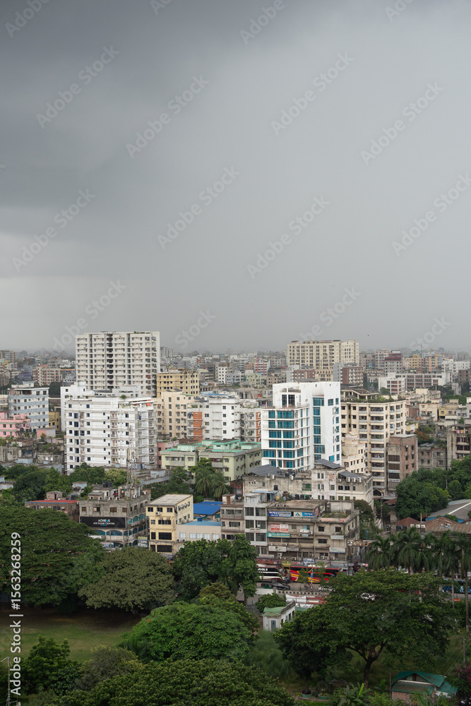 Obraz premium High-Rise Buildings and Dense Urban Skyline with Lush Greenery under Overcast Sky in Modern Metropolitan Cityscape