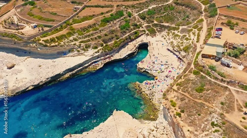 Famous St. Peter's Pool on summer. Drone view, people swimming, beach. Malta 