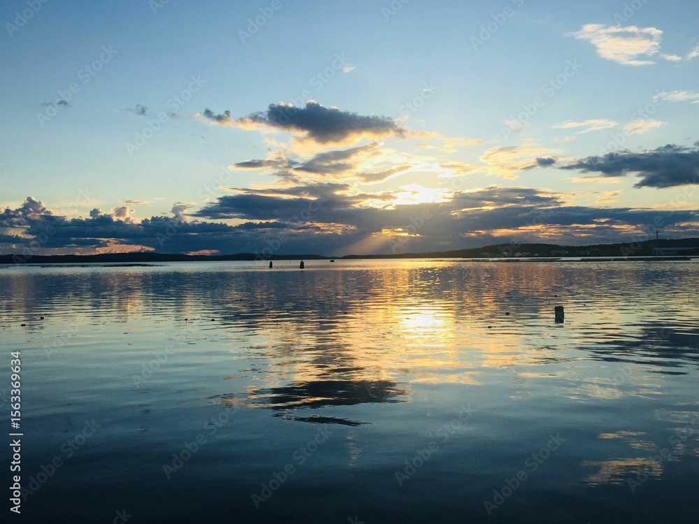 Naklejka premium Sunset over a lake with clouds reflecting from water