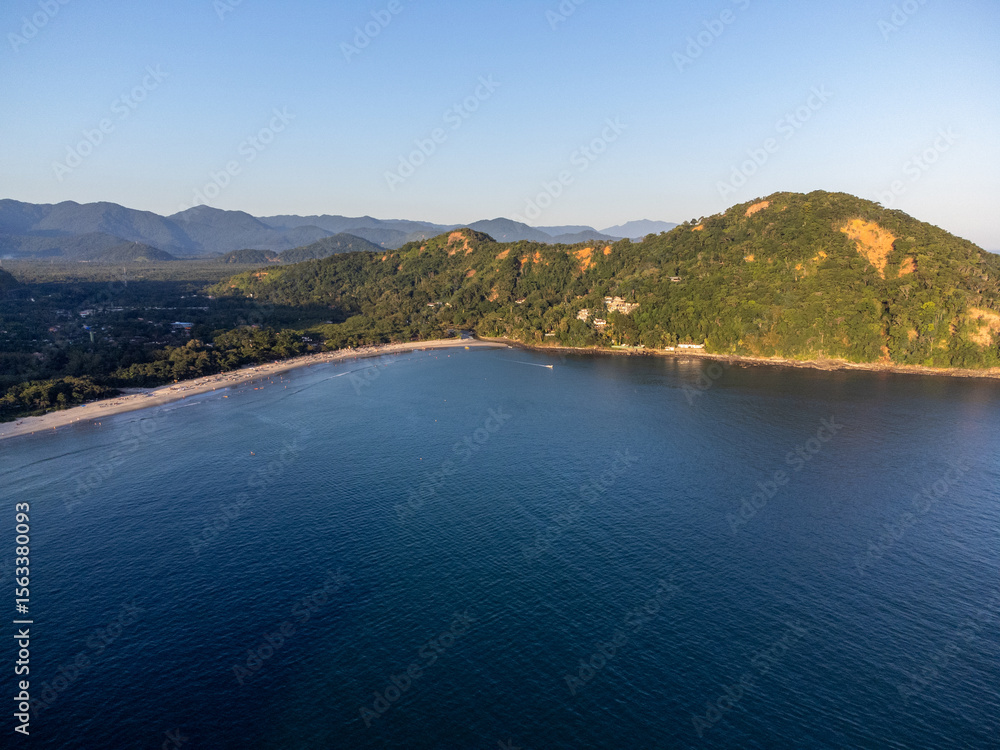 Obraz premium Sunset light on beach amidst mountains