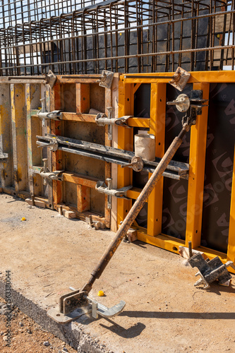 Adjustable steel prop supporting formwork on a construction site.