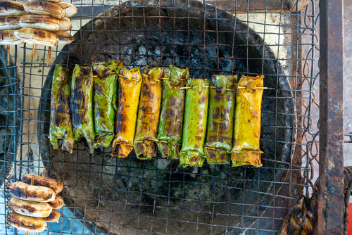 Photos Traditional Grilled Banana Leaf Parcels on Charcoal Stove in Southeast Asia