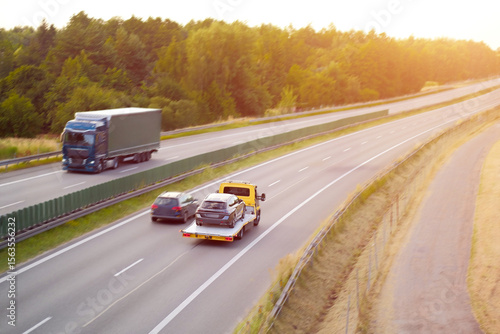 Car Being Towed on Flatbed Truck Along Highway at Sunset