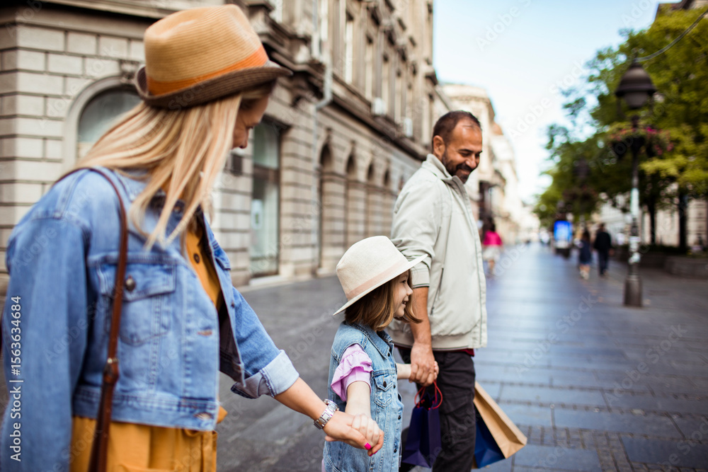 Happy family walking with daughter in city street on sunny day Happy family walking with daughter in city street on sunny day