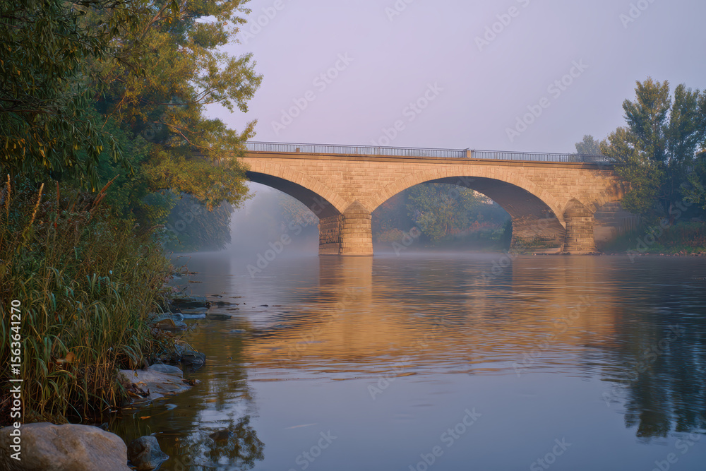 Fototapeta premium Historic Stone Arch Bridge Spanning a Serene River