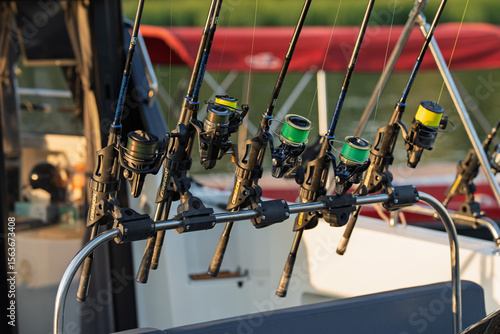 Fishing gear on yacht deck with reels, rods, and nautical equipment during marine adventure under clear sky