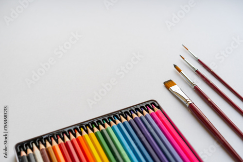 Art supplies on white background including colored pencils and paint brushes, symbolizing creativity, childhood art, and school learning tools