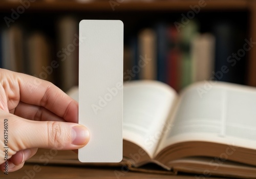 Blank bookmark mockup held over open book for branding and promotion use