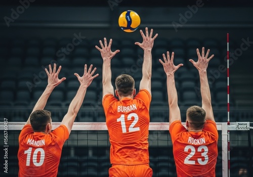 Volleyball players jump to block the ball in a competitive match action