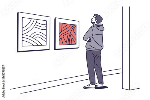 A man in a grey hoodie stands with his arms crossed contemplating abstract art displayed on a white gallery wall