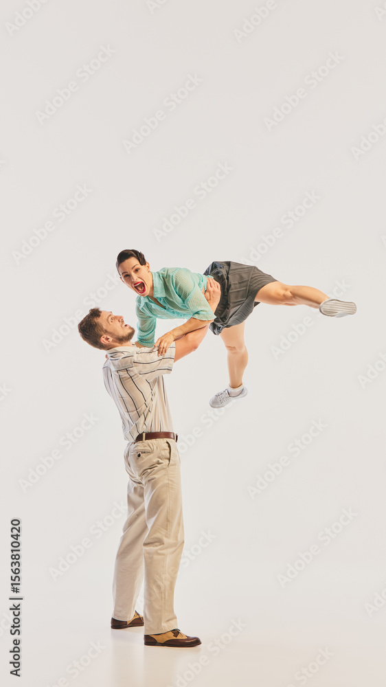 A Caucasian man lifts his partner in a joyful retro dance pose, capturing movement and excitement. Concept of vintage dance enthusiasm and energetic motion. A Caucasian man lifts his partner in a joyful retro dance pose, capturing movement and excitement. Concept of vintage dance enthusiasm and energetic motion.