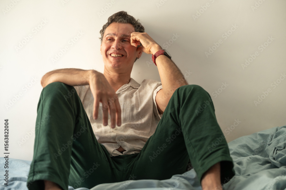 Obraz premium Smiling mature man relaxing on bed enjoying his free time