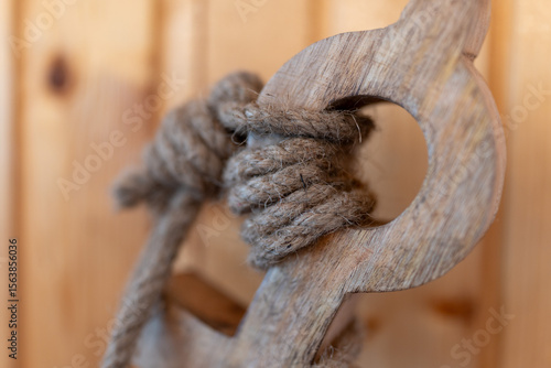 Close-up of a rope tied to an anchor, used as a decorative element. Nautical-themed decor symbolizing strength, stability, and marine heritage, ideal for coastal or maritime interior designs
