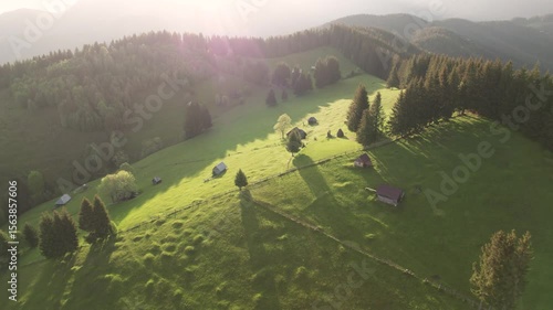 Aerial view of the Transylvanian village in the mountains, during summer. Sunset scene over the mountain valley in the Carpathian Mountains