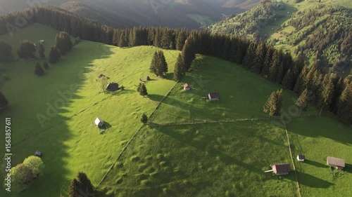 Aerial view of the Transylvanian village in the mountains, during summer. Sunset scene over the mountain valley in the Carpathian Mountains