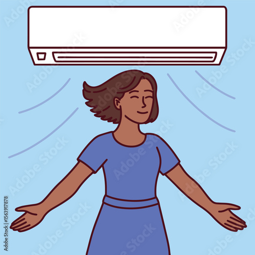 Dark skinned woman stands below a working air conditioner indoors. Her posture shows relief and balance in hot weather
