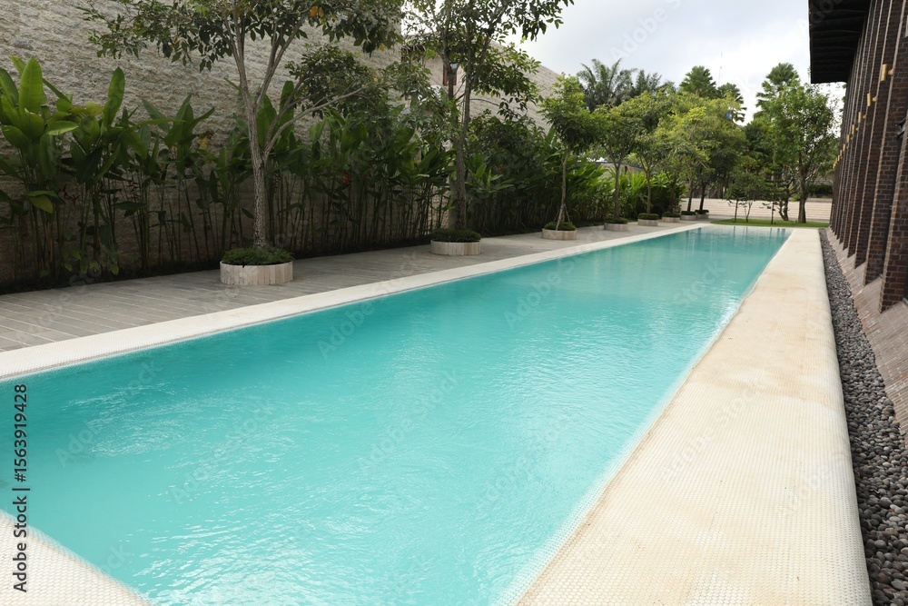 Fototapeta premium Outdoor swimming pool and green plants at luxury resort