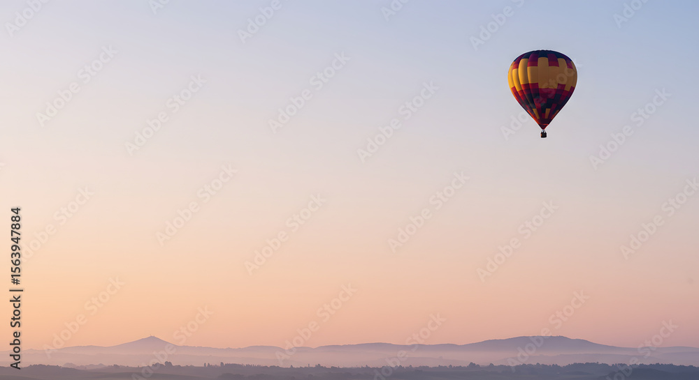 Obraz premium A single hot air balloon floating in the upper right third of a clear morning sky.