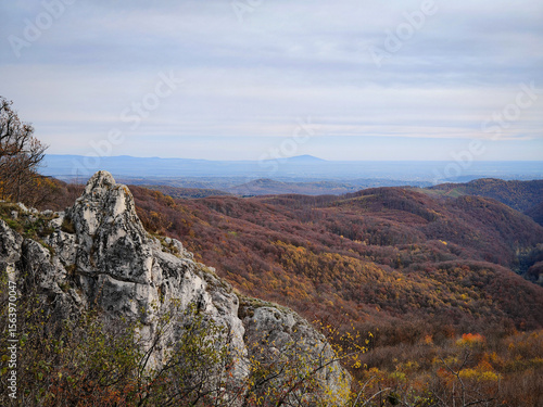 Принти на полотні View from Köpüs-kő with striking limestone formations and a distant glimpse of the Tokaj hills across the forested valleys of the Bükk Mountains