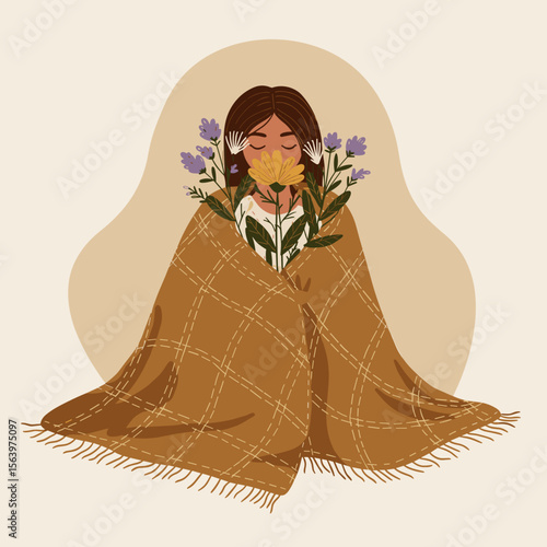 Woman sitting wrapped in a blanket holding flowers indoors  
