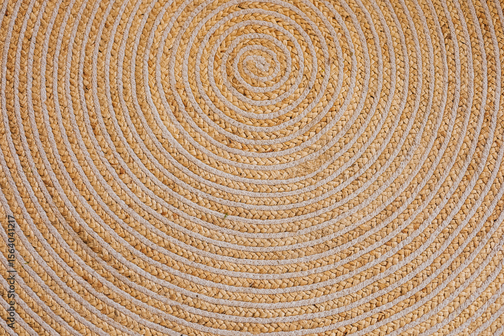 Fototapeta premium Intricate woven circular pattern displayed on a natural fiber rug in a cozy room setting