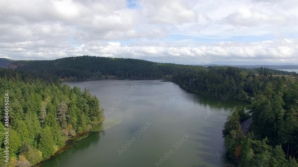 Scenic aerial view of road and forest near tranquil lake on cloudy day Scenic aerial view of road and forest near tranquil lake on cloudy day