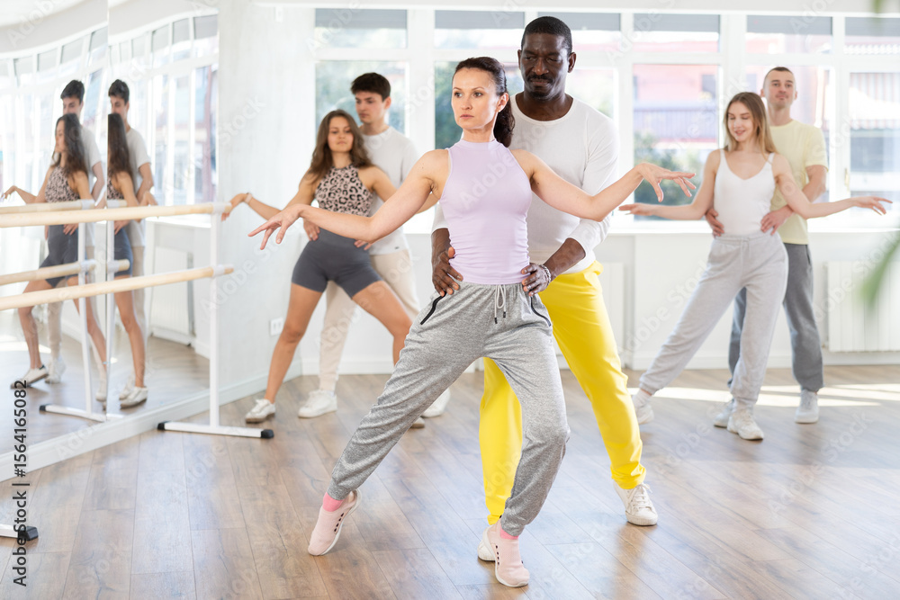 Fototapeta premium With unhurried music, woman with African man in couple spins to rhythm of waltz during lesson for novice students. Classes in mini-groups for those who want to learn dancing