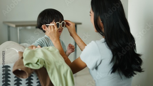 Photography Mom putting sunglasses on her son while doing laundry at home