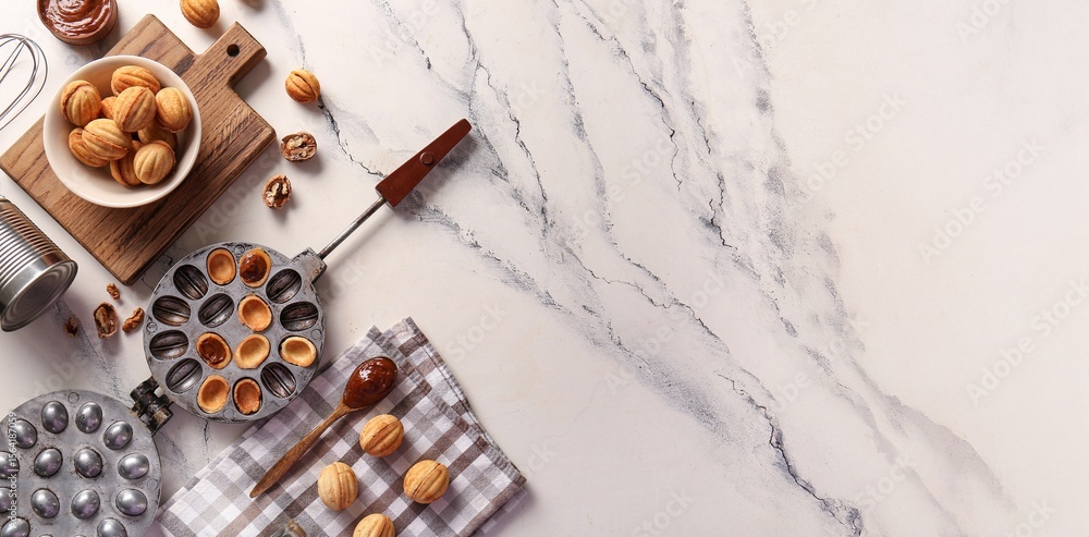 Fototapeta premium Composition with tasty walnut shaped cookies, boiled condensed milk and baking form on light background with space for text
