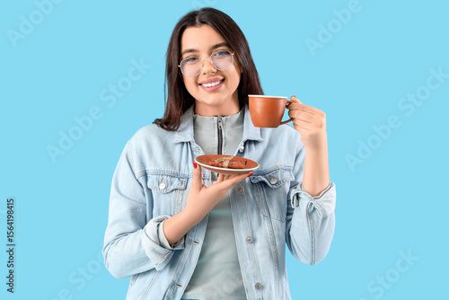 Young woman in eyeglasses with cup of tea on blue background