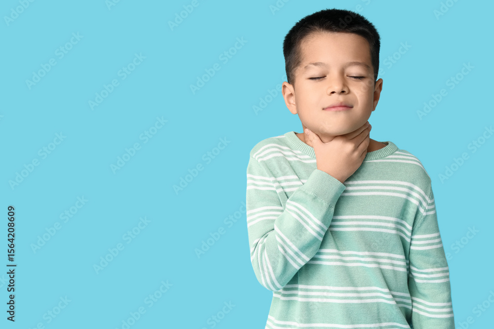 Ill little Asian boy with sore throat on blue background Ill little Asian boy with sore throat on blue background
