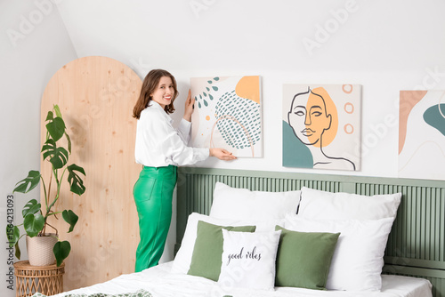Young woman hanging paintin...