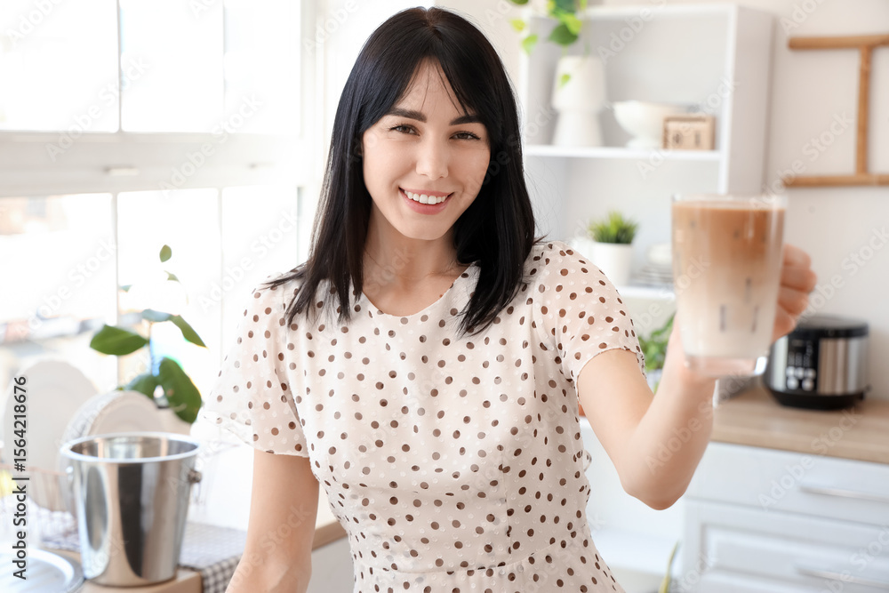 Young woman with glass of iced latte in kitchen Young woman with glass of iced latte in kitchen