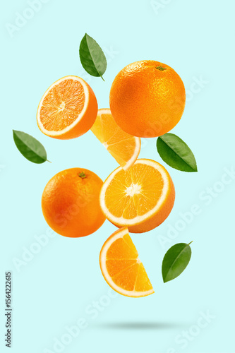  Falling orange with cut in half and leaves isolated on light green background.