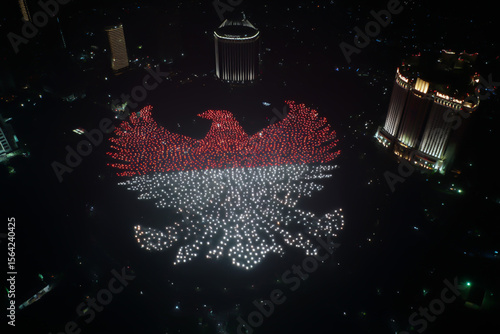 Drone formation forming Garuda Pancasila in red and white lights, captured at night above Jakarta skyline, ideal for Indonesian Independence Day themes and patriotic celebration visuals.