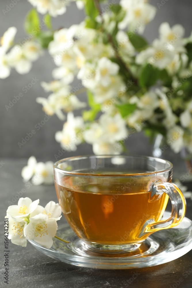 Aromatic jasmine tea and flowers on grey table Aromatic jasmine tea and flowers on grey table