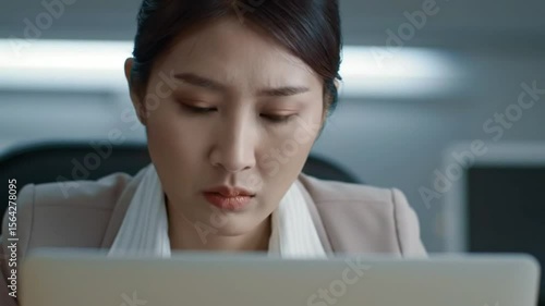 Serious Asian Businesswoman Concentrating on Laptop in Office