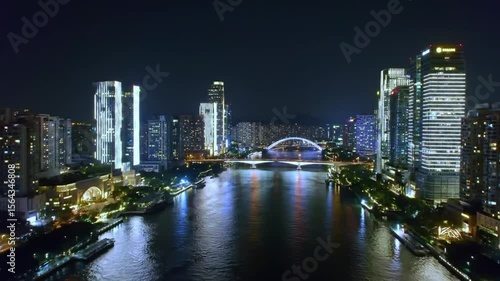 Wallpaper Mural Stunning aerial panorama of a modern city at night, featuring illuminated skyscrapers lining a river, with a brightly lit bridge connecting the banks. Torontodigital.ca