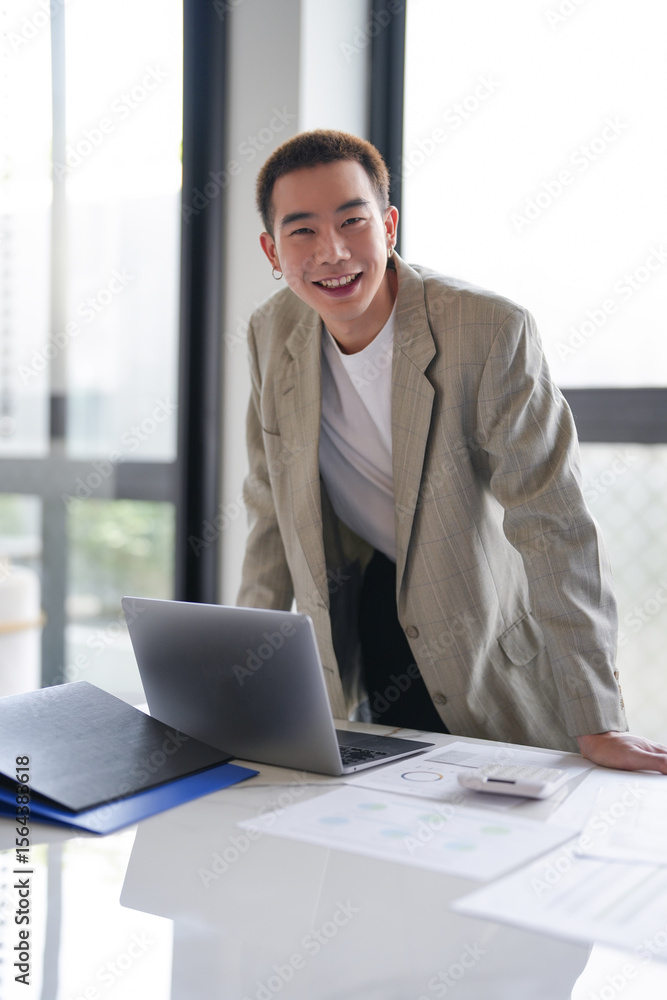 Smiling young Asian businessman in modern office. handsome asian man happy and friendly while working success job Smiling young Asian businessman in modern office. handsome asian man happy and friendly while working success job