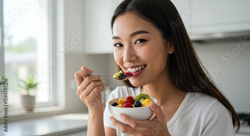 Woman eating fruit salad in kitchen